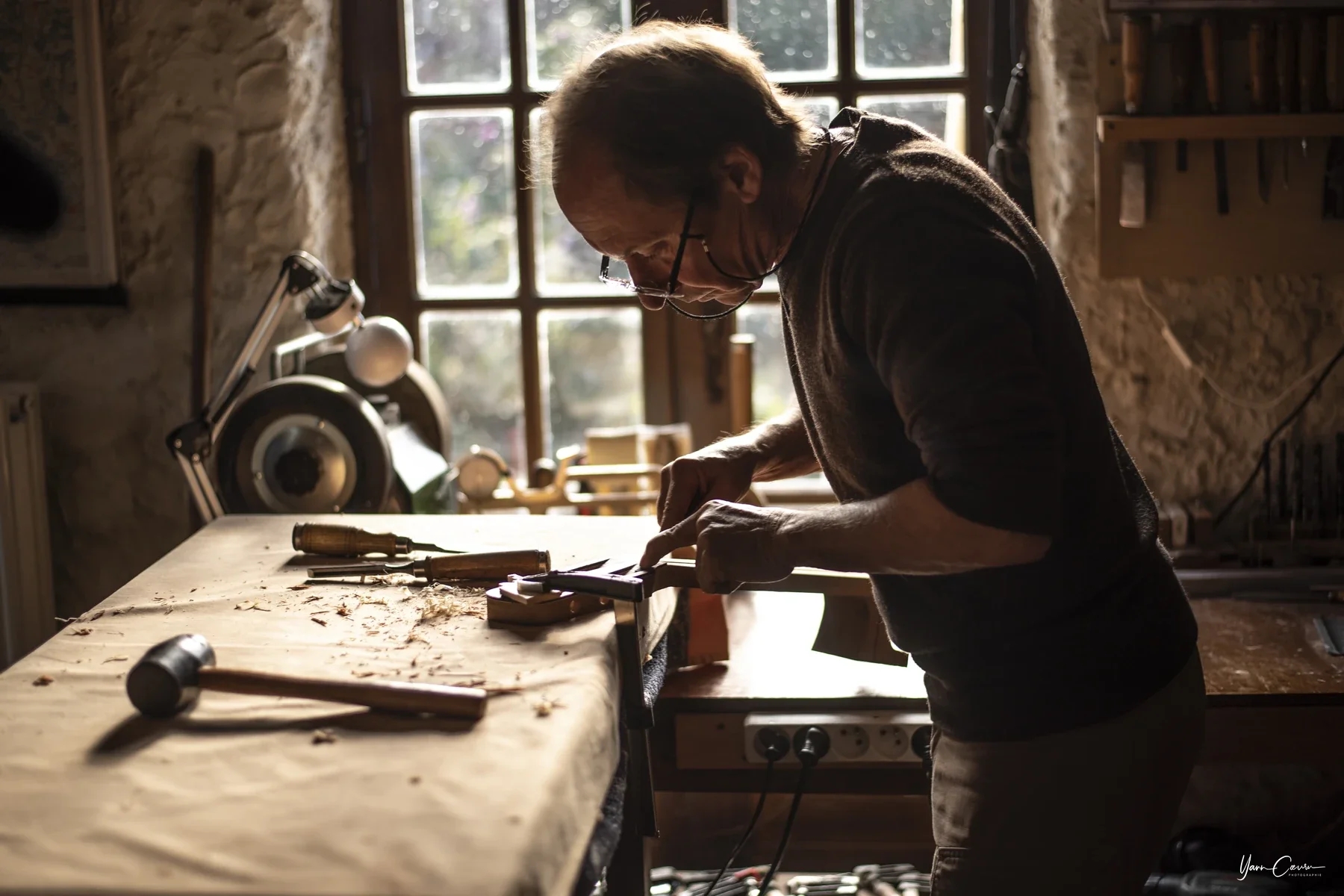 Artisan menuisier concentré dans son atelier, Entreprise photographiée à Saint genest de bauzon en lumière naturelle.