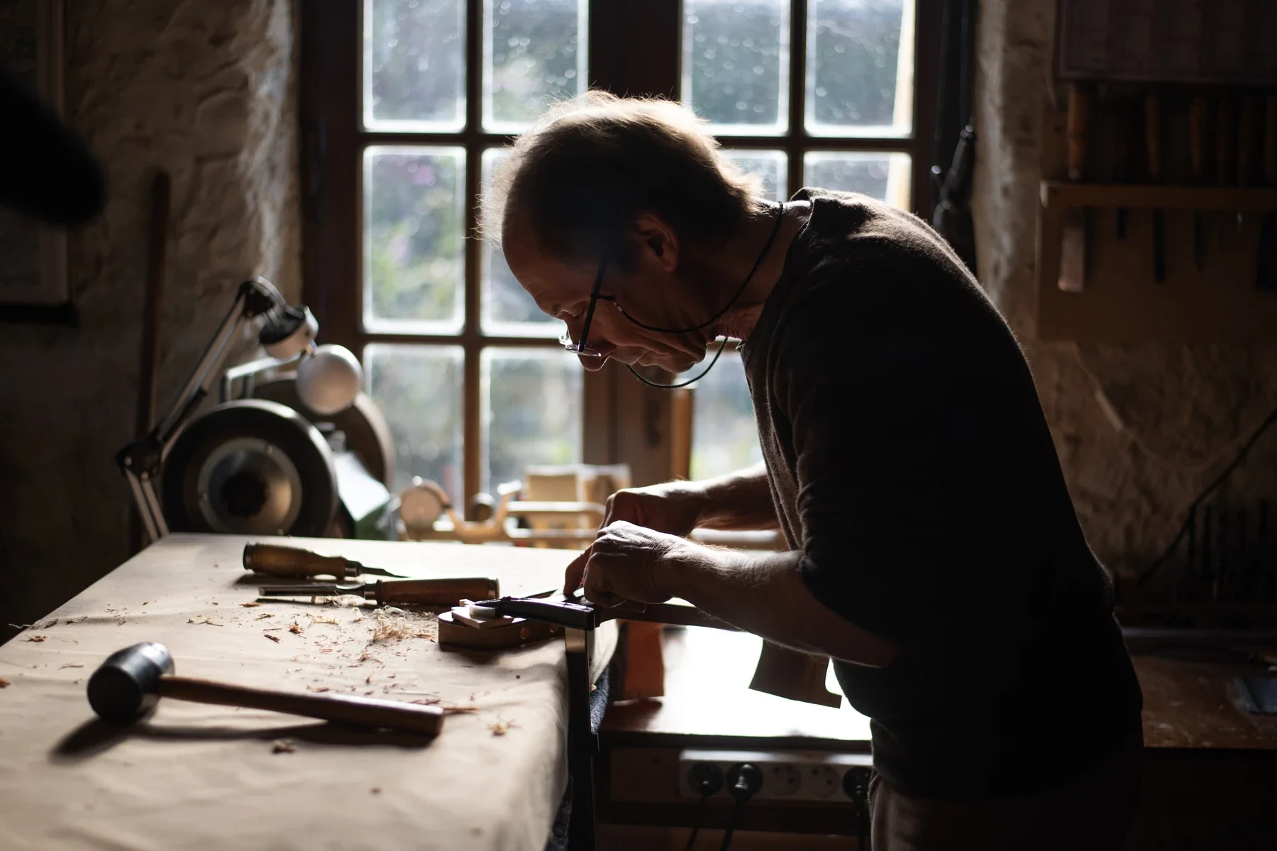 Artisan concentré dans son atelier, portrait Entreprise à Saint genest de bauzon en lumière naturelle.