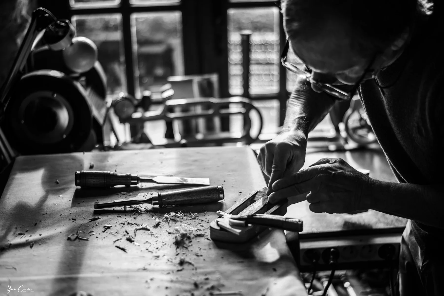 Artisan menuisier concentré sur son établi à Saint genest de bauzon, portrait Entreprise en noir et blanc.
