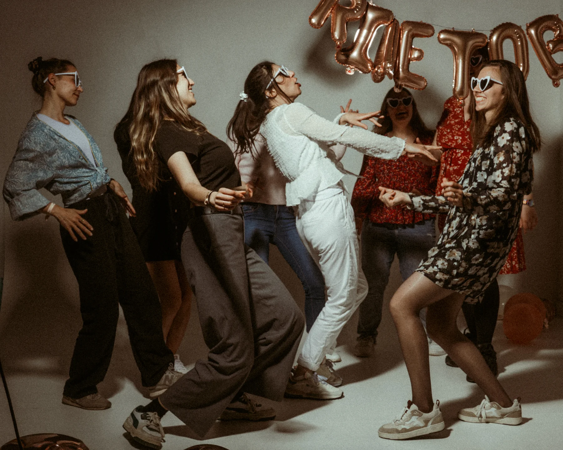 Groupe de femmes en studio célébrant un EVJF Ardèche avec ballons dorés et accessoires festifs