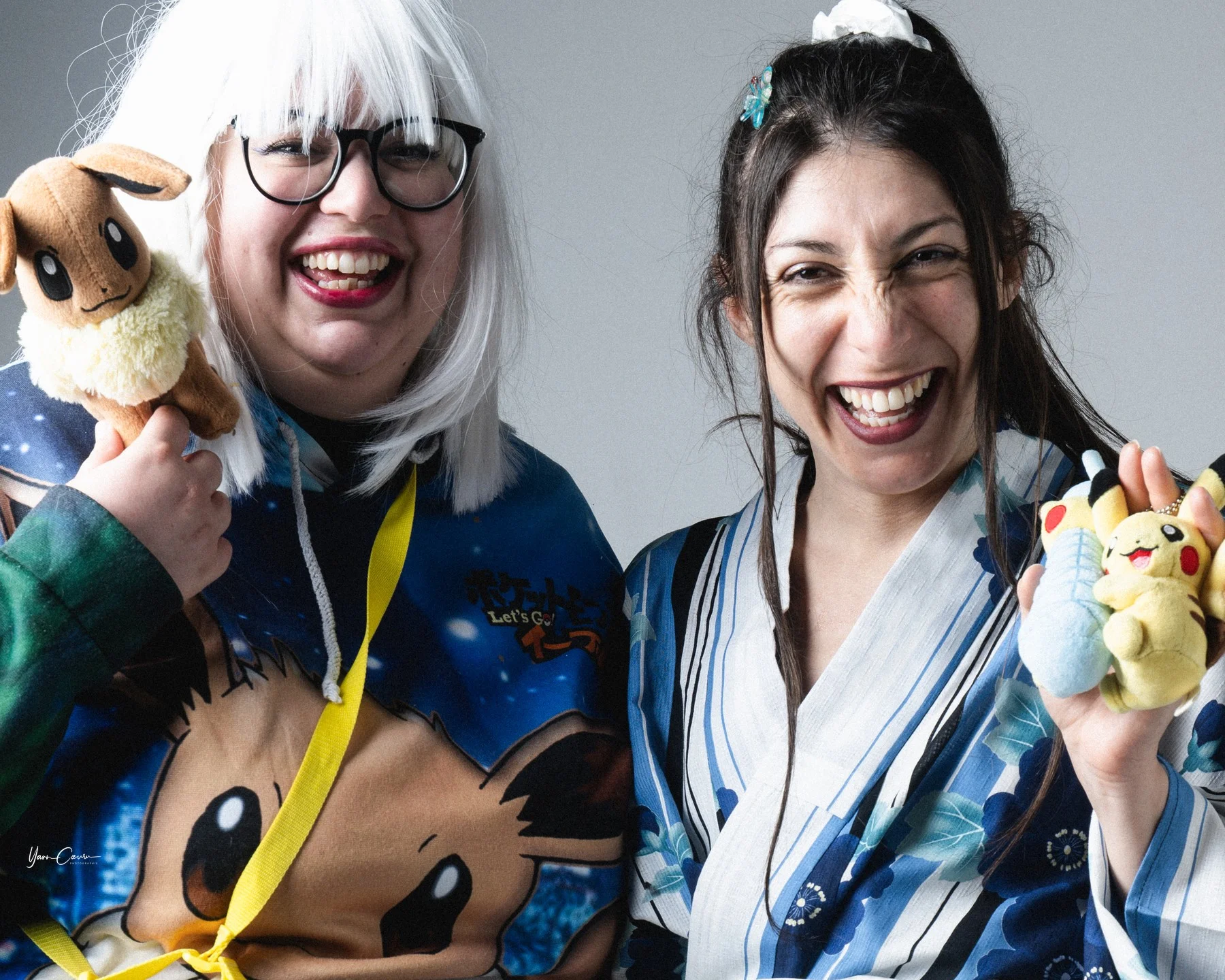 Deux femmes souriantes en costume thématique Pokémon posent en studio pour un EVJF Ardèche, holding peluches jaunes colorées