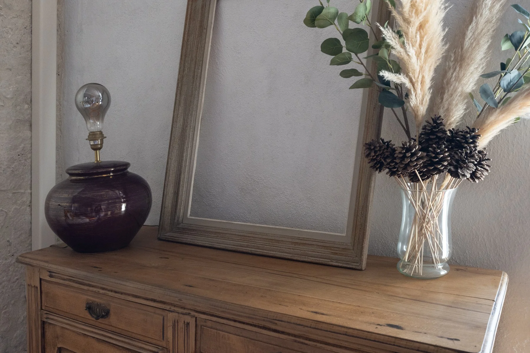 Décoration intérieure épurée : commode bois, miroir et vase avec fleurs séchées, photo immobilière Ardèche