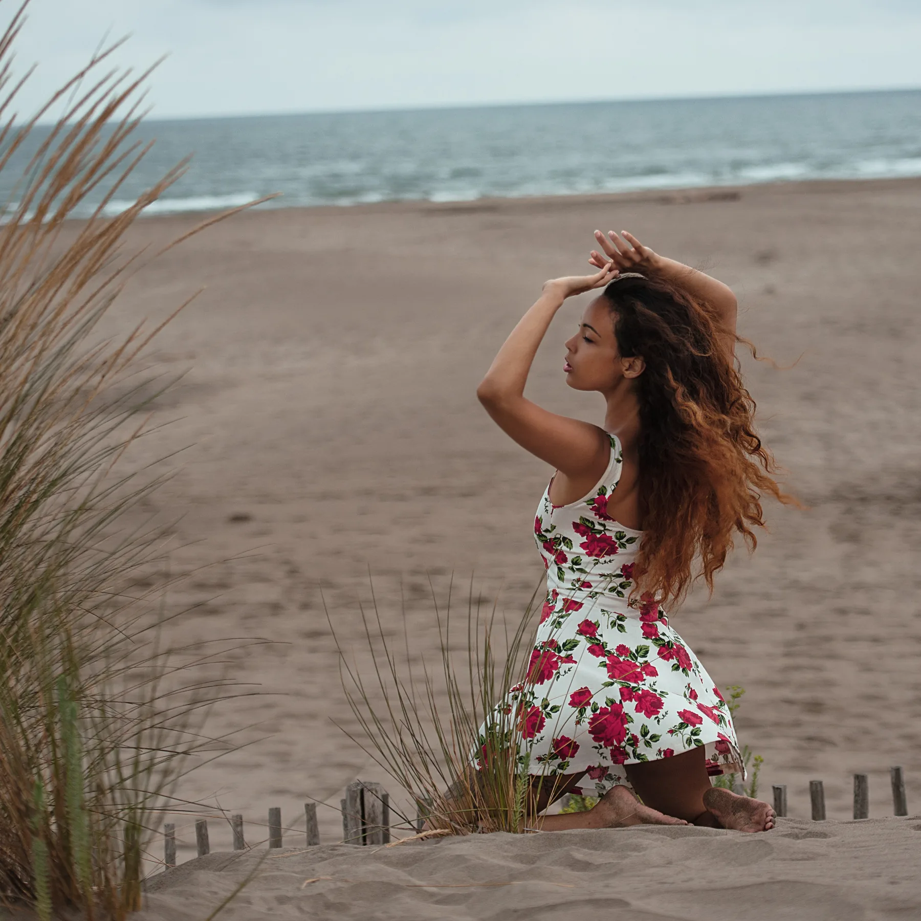 Femme en robe fleurie à la plage, cheveux longs au vent, séance plage Camargue en fin d'après-midi