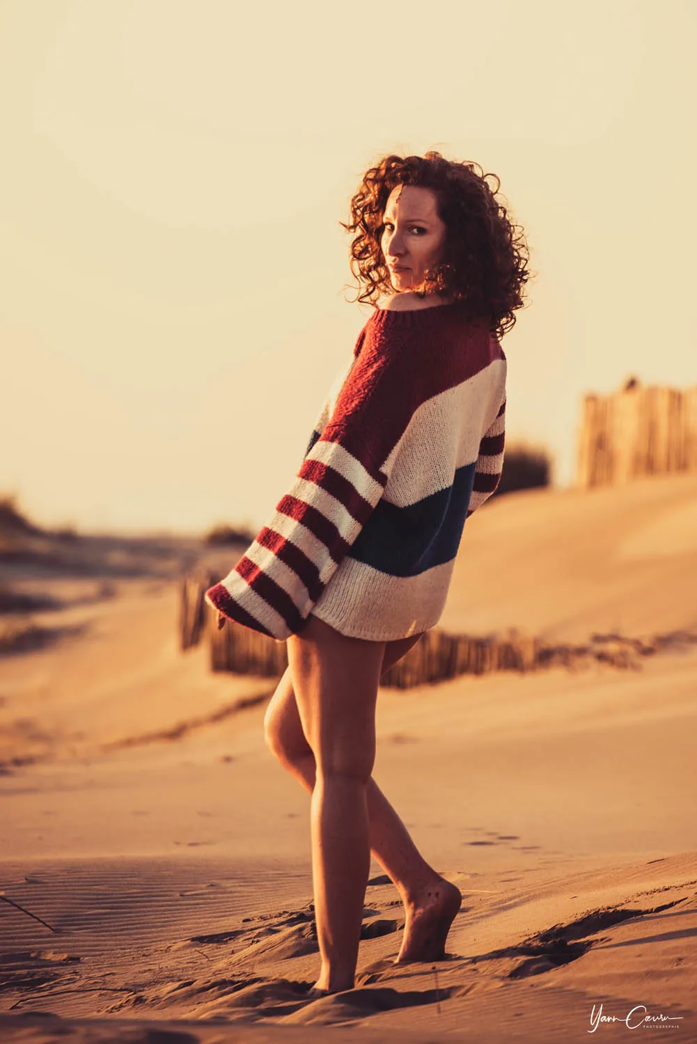 Femme en pull rayé à la plage au coucher de soleil, séance plage Camargue en lumière dorée